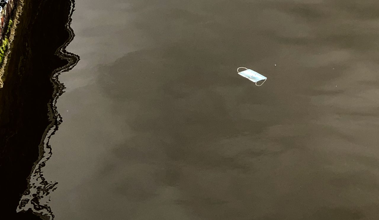 A face mask floating in a canal.