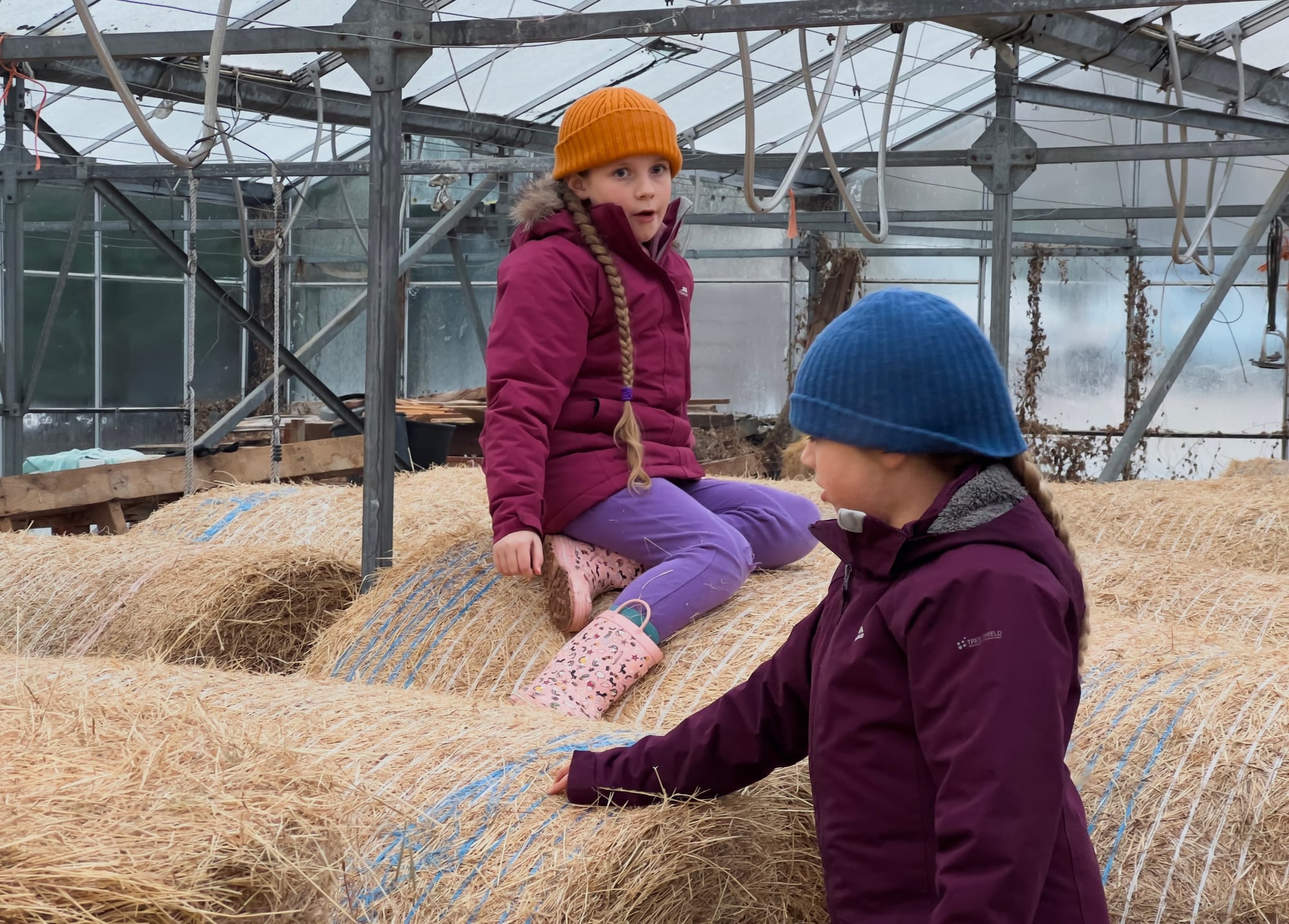 Two girls playing on hay bales at Spithandle Nursery